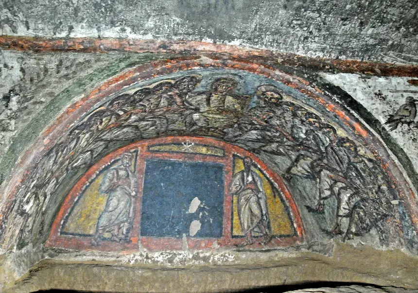 Gallery lined with loculi burial niches inside the Catacombs of Domitilla in Rome